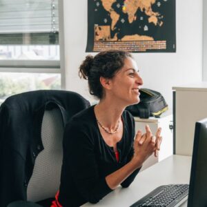 Une personne du pole audit est devant son ordinateur à son bureau et sourit.