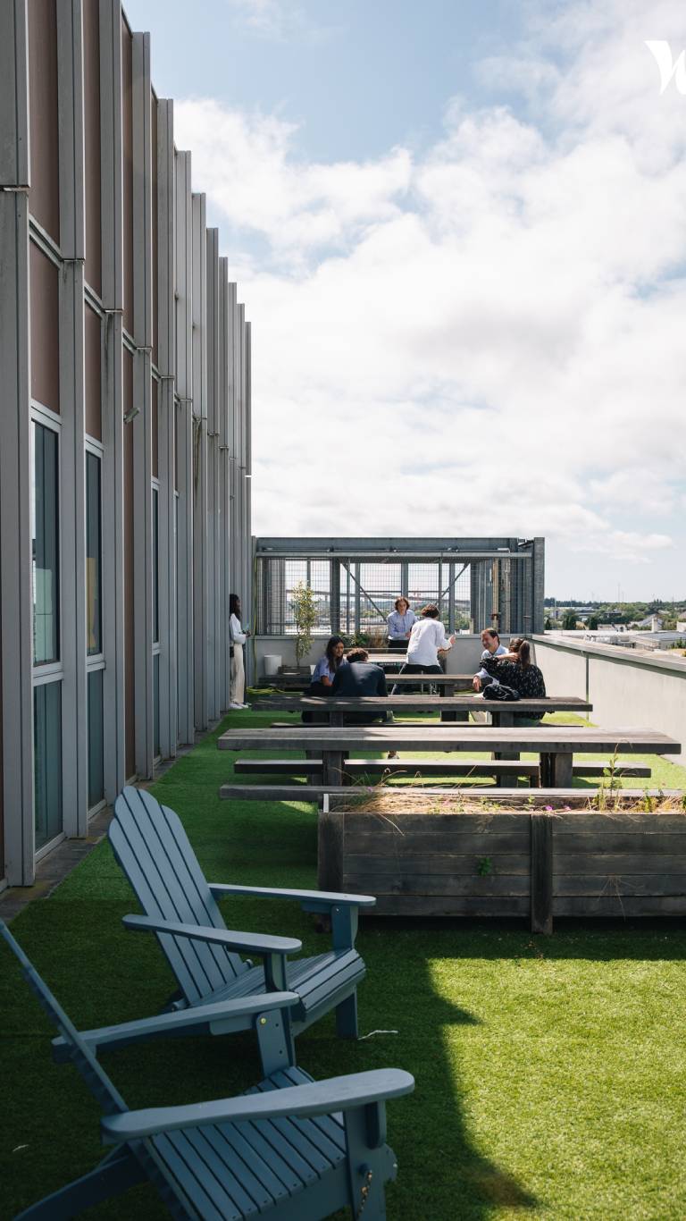 Espace de détente extérieur sur le toit-terrasse moderne où des collaborateurs de HLP Audit discutent autour d'une table.