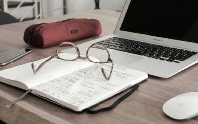 Carnet ouvert avec des notes manuscrites et lunettes posées, symbolisant l'analyse et l'évaluation d'entreprise détaillée.