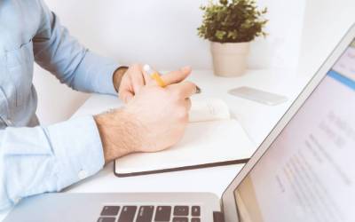 Professionnel prenant des notes dans un carnet, illustrant le travail de conseil en restructuration d'entreprise.