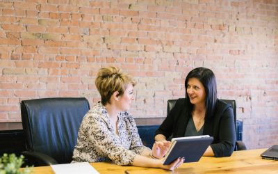 Deux professionnelles en discussion consultant une tablette, représentant le conseil social et l'accompagnement RH.