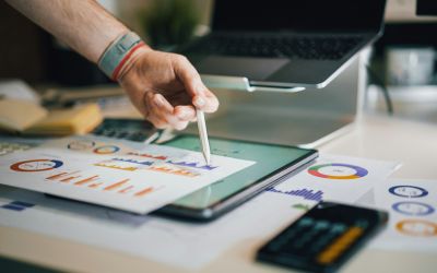 Main pointant avec un stylet des graphiques de reporting financier sur une tablette, illustrant le pilotage d'entreprise.