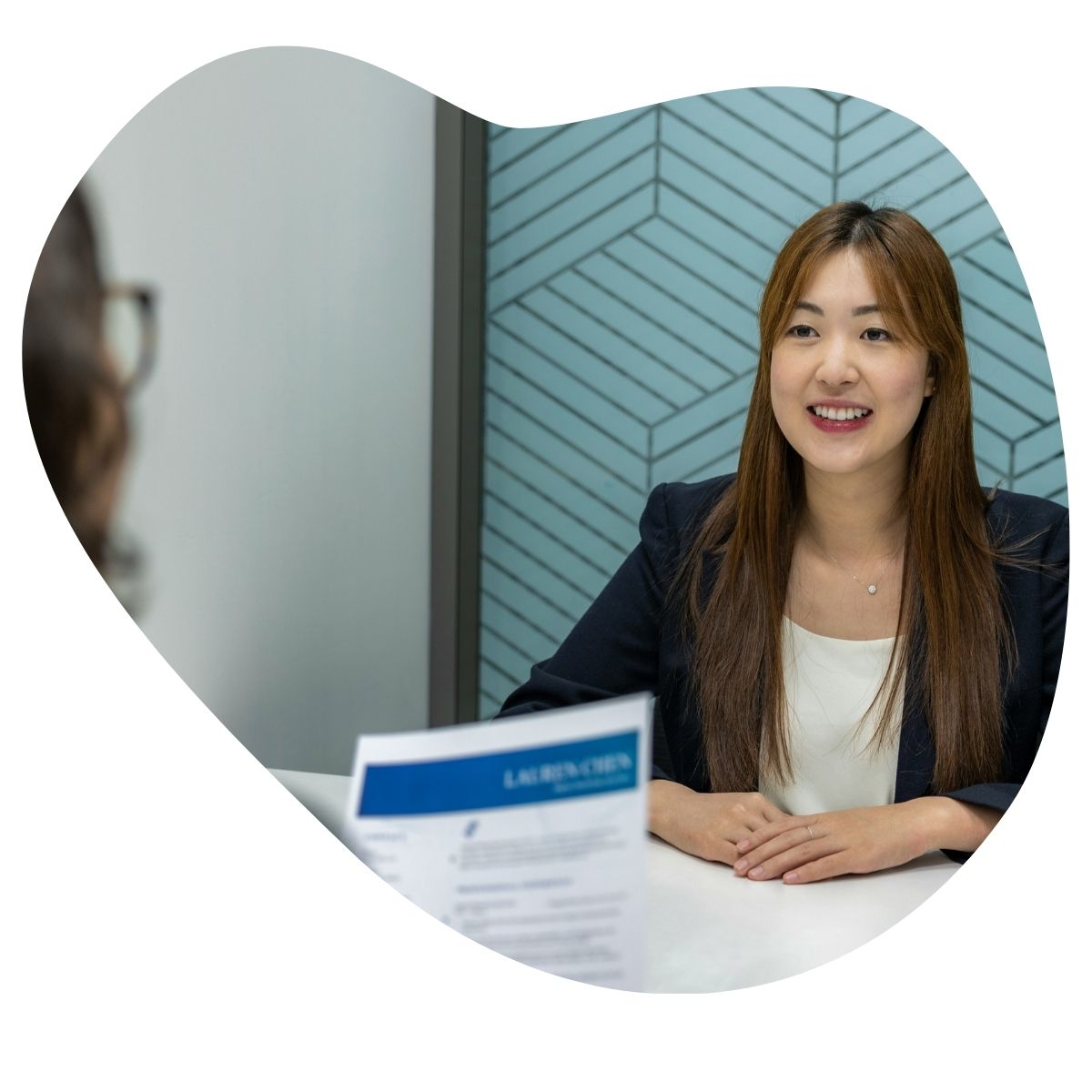 Une consultante RH souriante en entretien, avec un CV posé sur la table.